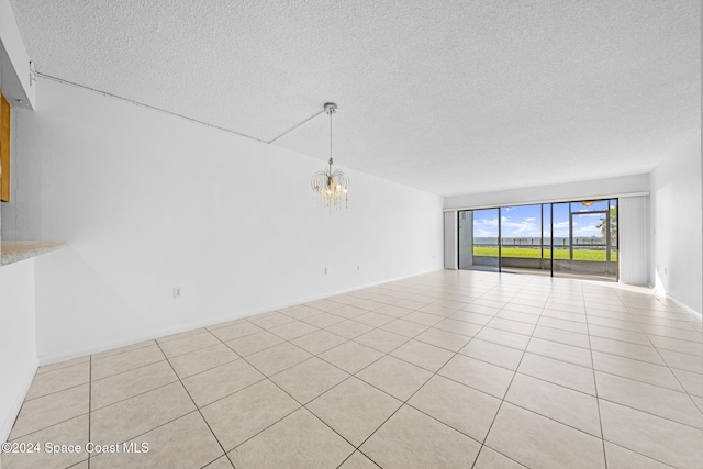 unfurnished living room featuring a notable chandelier, light tile patterned floors, and a textured ceiling