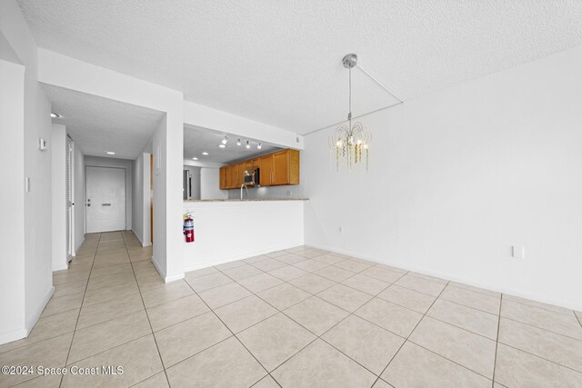 unfurnished living room with a chandelier, light tile patterned floors, and a textured ceiling