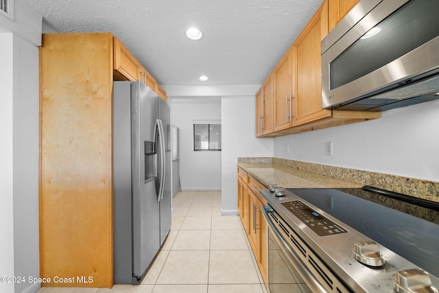 kitchen featuring appliances with stainless steel finishes, a textured ceiling, and light tile patterned floors