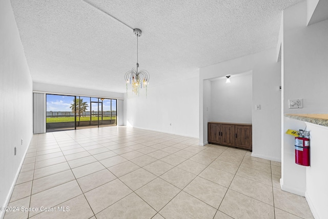 unfurnished living room with light tile patterned floors, a textured ceiling, and a notable chandelier