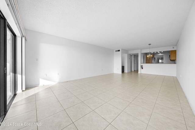 unfurnished living room with light tile patterned floors, a textured ceiling, and a notable chandelier