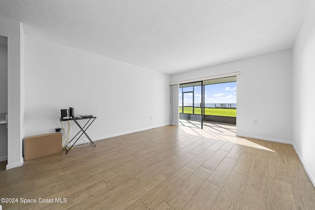 unfurnished room with light hardwood / wood-style floors and a textured ceiling