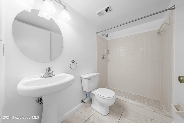 bathroom with tile patterned flooring, tiled shower, and toilet