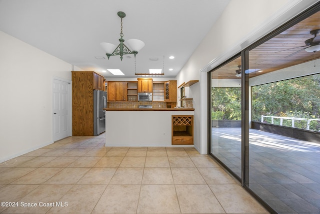 kitchen with pendant lighting, backsplash, ceiling fan with notable chandelier, appliances with stainless steel finishes, and light tile patterned flooring