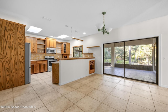 kitchen featuring appliances with stainless steel finishes, backsplash, a skylight, and light tile patterned floors