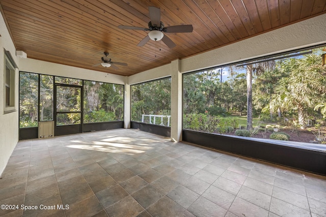 unfurnished sunroom with ceiling fan, plenty of natural light, and wood ceiling