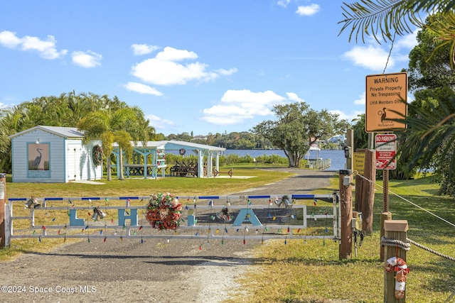 view of property's community with a yard, a water view, and an outdoor structure