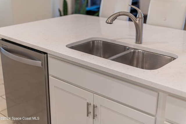 interior details with light stone counters, dishwasher, sink, and white cabinets