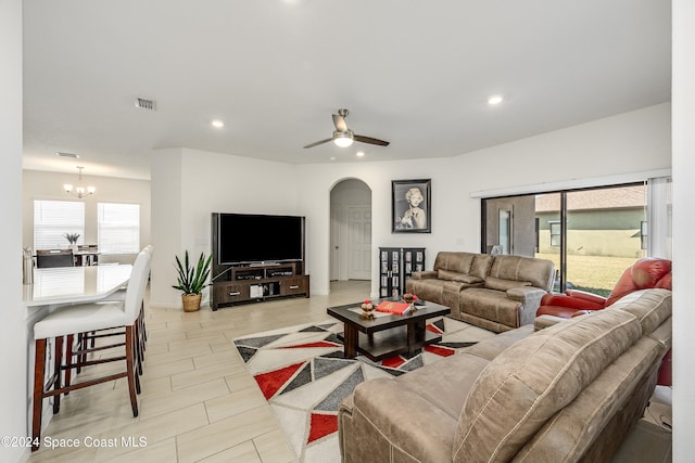 tiled living room featuring ceiling fan with notable chandelier