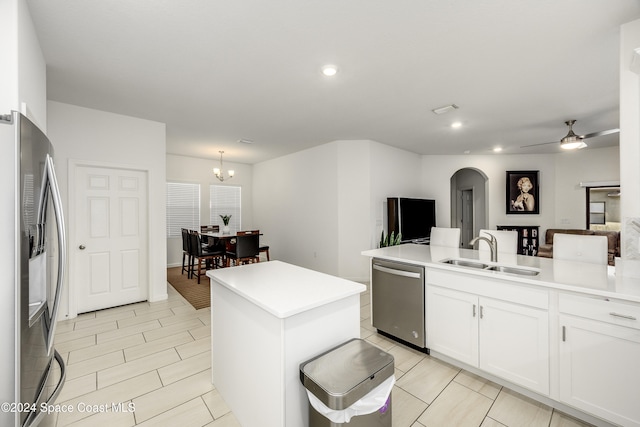 kitchen with sink, appliances with stainless steel finishes, a center island, white cabinets, and ceiling fan with notable chandelier