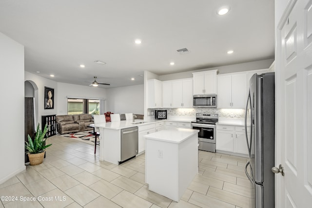 kitchen with a breakfast bar, sink, appliances with stainless steel finishes, kitchen peninsula, and a kitchen island