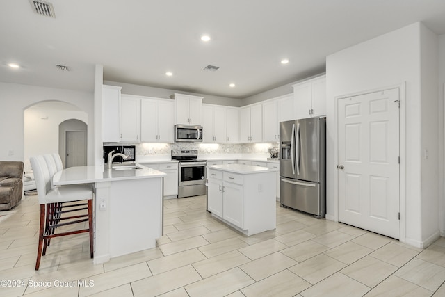 kitchen with appliances with stainless steel finishes, a kitchen island with sink, sink, and white cabinets