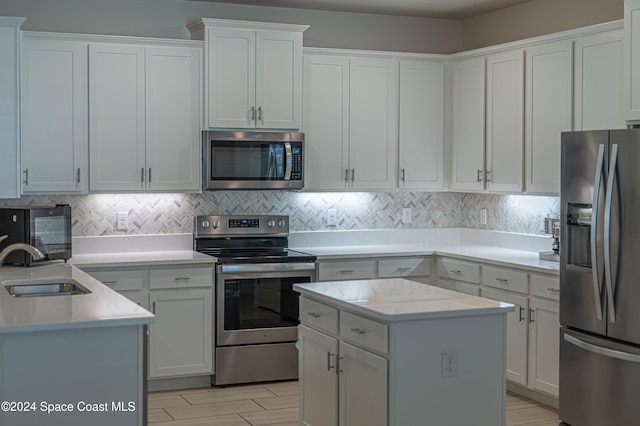 kitchen with white cabinetry, appliances with stainless steel finishes, a center island, and sink