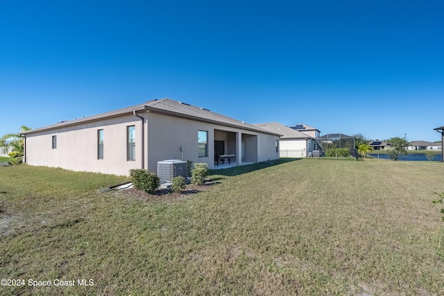 rear view of property with a yard, a lanai, and central AC unit