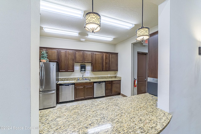 kitchen featuring pendant lighting, sink, dark brown cabinets, stainless steel appliances, and a textured ceiling