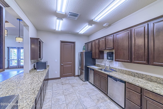 kitchen with sink, hanging light fixtures, a textured ceiling, stainless steel appliances, and light stone countertops