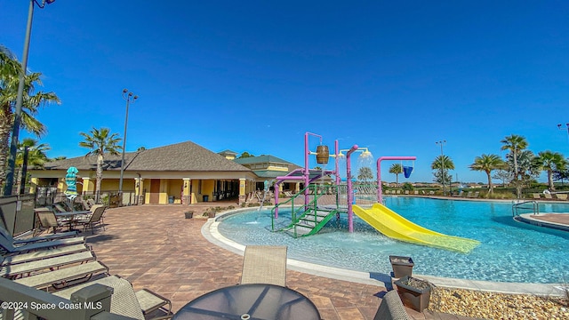 view of pool with pool water feature, a playground, and a water slide