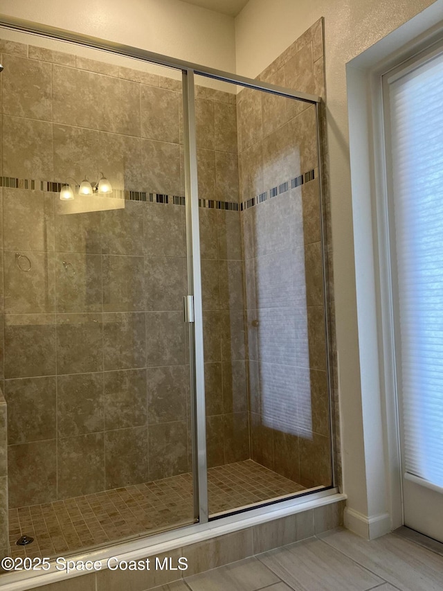 bathroom with a shower with shower door and tile patterned floors