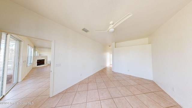 empty room with ceiling fan, light tile patterned floors, and vaulted ceiling