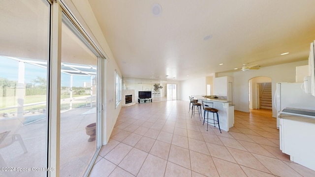 kitchen with white cabinetry, ceiling fan, white fridge, a kitchen bar, and light tile patterned flooring