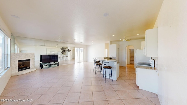 kitchen with white cabinetry, a center island, ceiling fan, a kitchen bar, and light tile patterned floors