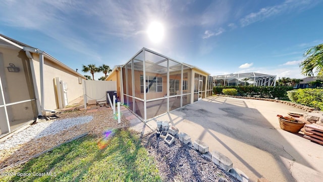 rear view of property featuring a patio area and glass enclosure