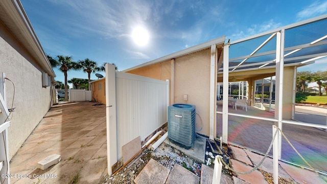 view of side of home featuring a lanai and central air condition unit