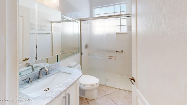 bathroom with tile patterned floors, vanity, a shower with shower door, and toilet