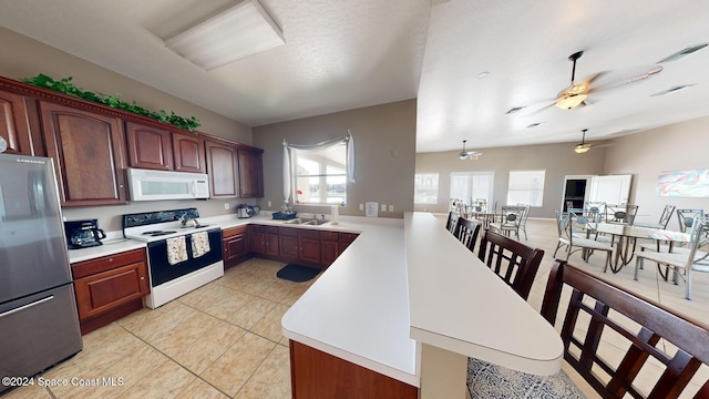 kitchen with kitchen peninsula, white appliances, ceiling fan, sink, and hanging light fixtures