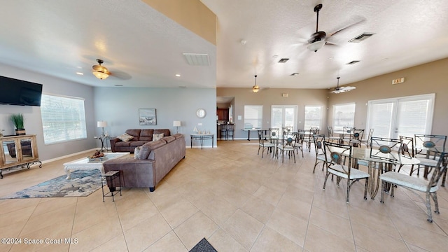 living room featuring ceiling fan, light tile patterned floors, and a healthy amount of sunlight