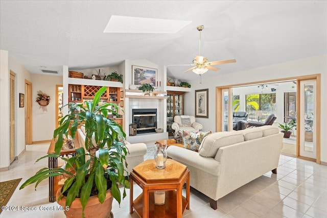 tiled living room with ceiling fan and vaulted ceiling with skylight