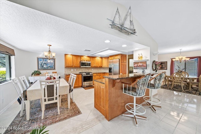 kitchen with a chandelier, hanging light fixtures, a kitchen island, and stainless steel appliances