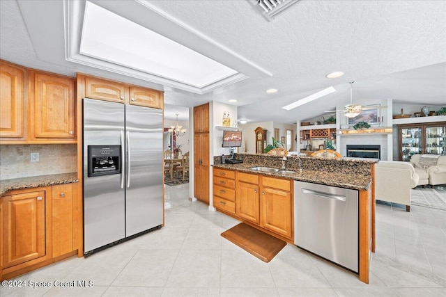 kitchen featuring dark stone countertops, stainless steel appliances, lofted ceiling, and sink