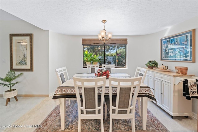 tiled dining space with a notable chandelier and a textured ceiling