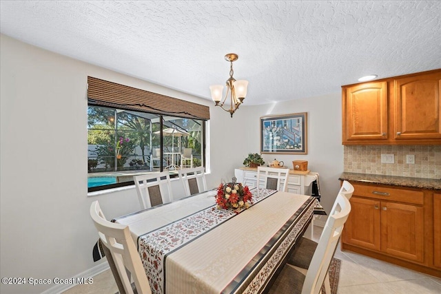 tiled dining room with a textured ceiling and an inviting chandelier