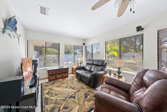 living room with a textured ceiling and ceiling fan