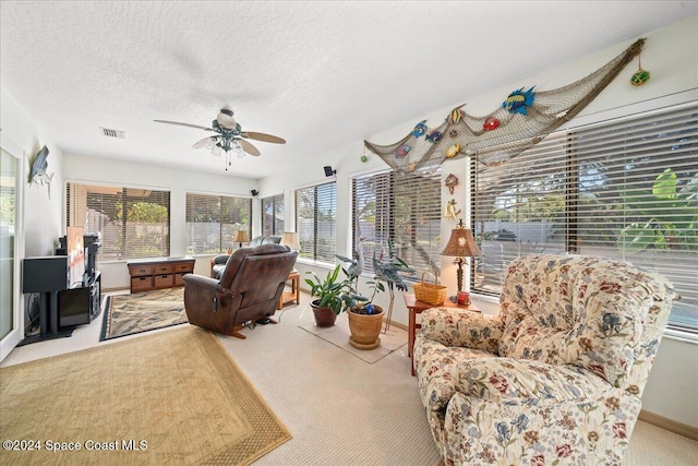 living room with carpet flooring, ceiling fan, and a textured ceiling