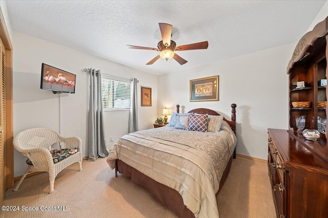 carpeted bedroom with ceiling fan and a textured ceiling