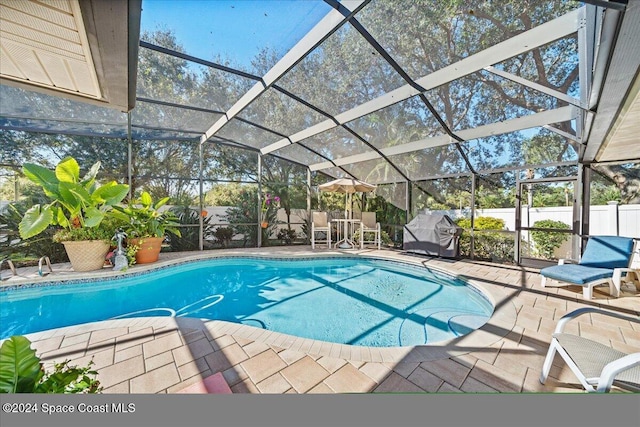 view of swimming pool featuring glass enclosure, a grill, and a patio area