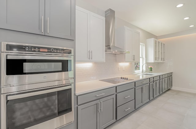 kitchen featuring sink, wall chimney exhaust hood, black electric cooktop, double oven, and white cabinetry