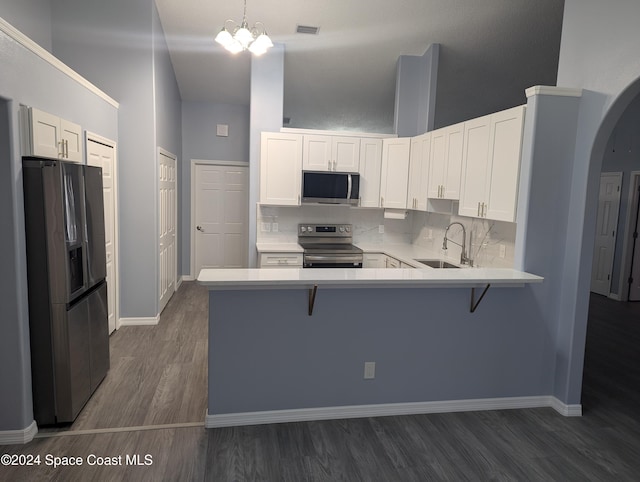 kitchen with kitchen peninsula, stainless steel appliances, sink, pendant lighting, and white cabinetry