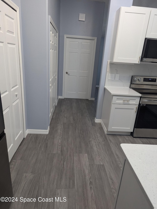 kitchen featuring light stone countertops, appliances with stainless steel finishes, dark hardwood / wood-style floors, and white cabinetry