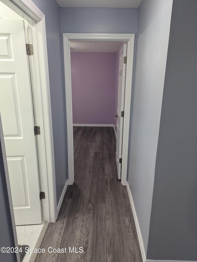 corridor featuring a textured ceiling and dark hardwood / wood-style floors