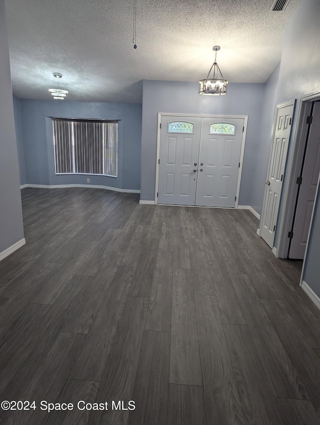 entrance foyer featuring a chandelier, a textured ceiling, and dark hardwood / wood-style flooring