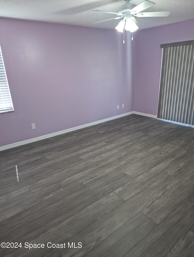 empty room with a textured ceiling, ceiling fan, and dark hardwood / wood-style floors