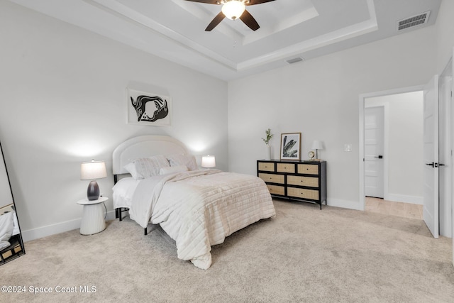 carpeted bedroom featuring a tray ceiling and ceiling fan