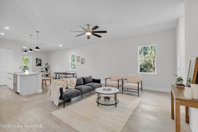 living room featuring light wood-type flooring, ceiling fan, and sink