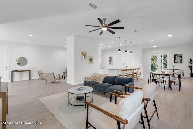 living room featuring ceiling fan, light hardwood / wood-style flooring, french doors, and sink