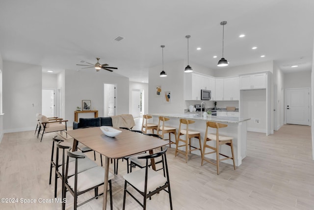 dining room with ceiling fan, light hardwood / wood-style floors, and sink