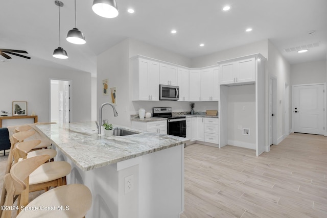 kitchen featuring light stone countertops, stainless steel appliances, sink, pendant lighting, and white cabinets